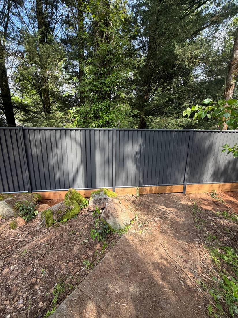 Charcoal Colorbond steel privacy fence set on a cedar kickboard in a Portland, OR backyard