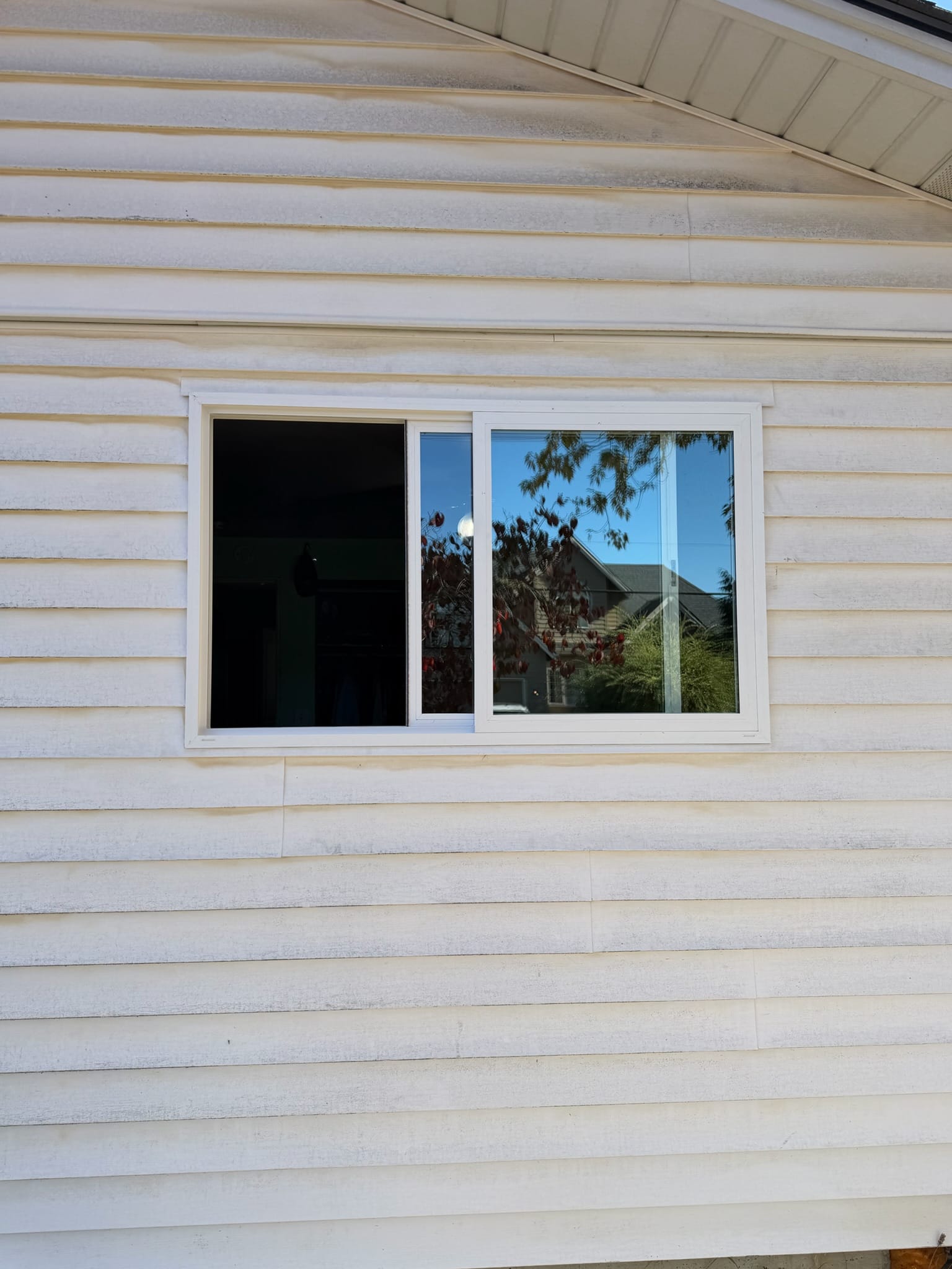A new white vinyl window Gorilla Works fit into the existing opening of an older home with lap siding