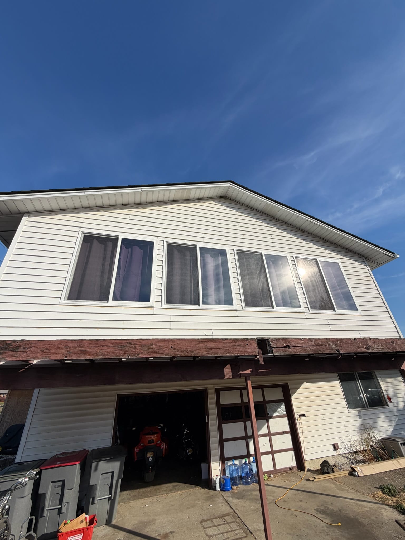 A row of new white vinyl windows Gorilla Works installed on the second story of a Portland area home, high above the driveway