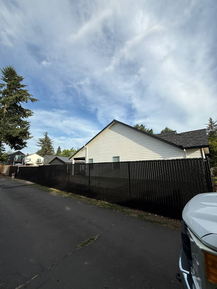 Dark steel privacy fence running along a driveway beside a house in the Portland, OR area