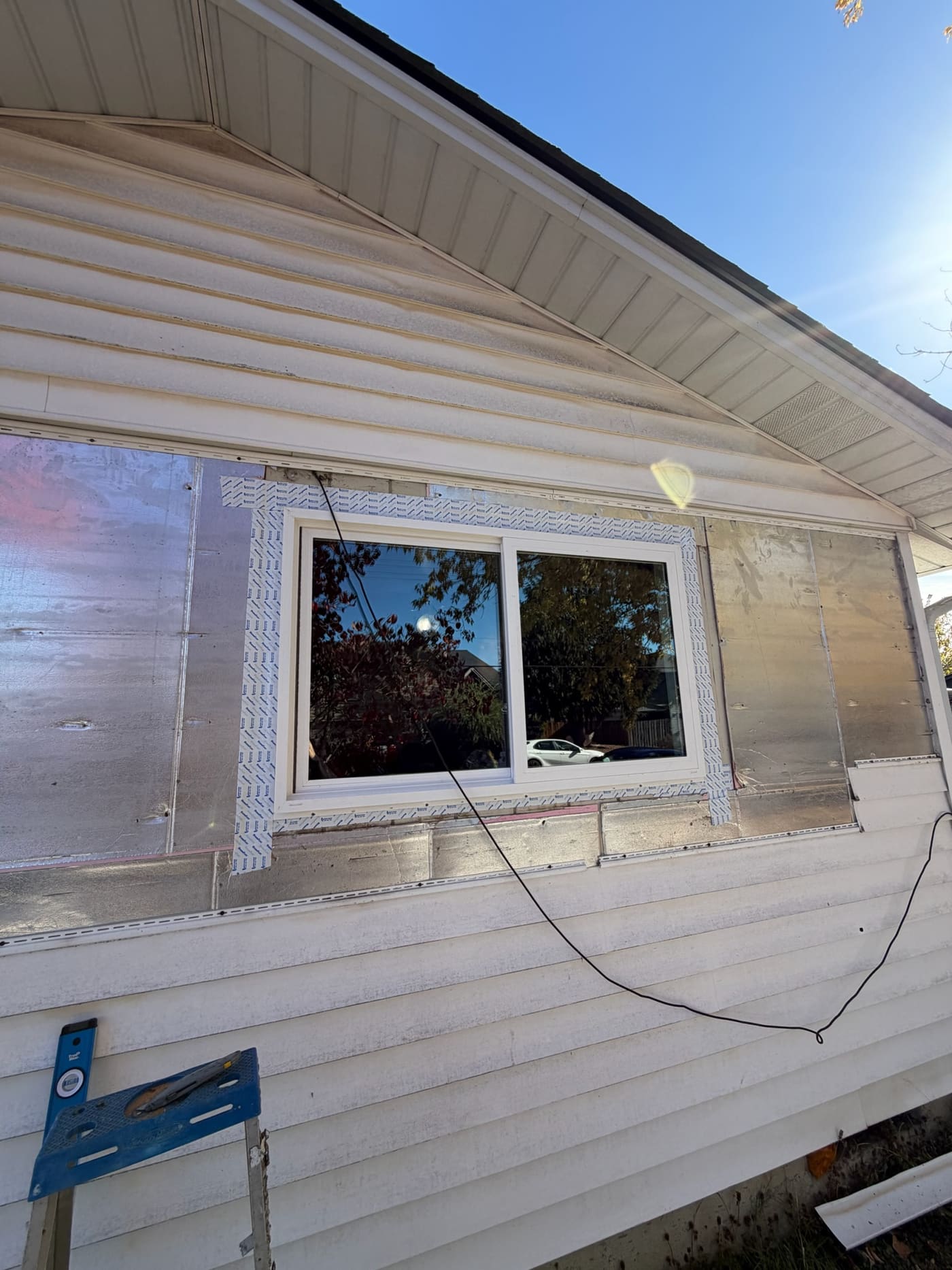 A full-frame window install: the new slider is flashed into the wall with the old siding removed around it