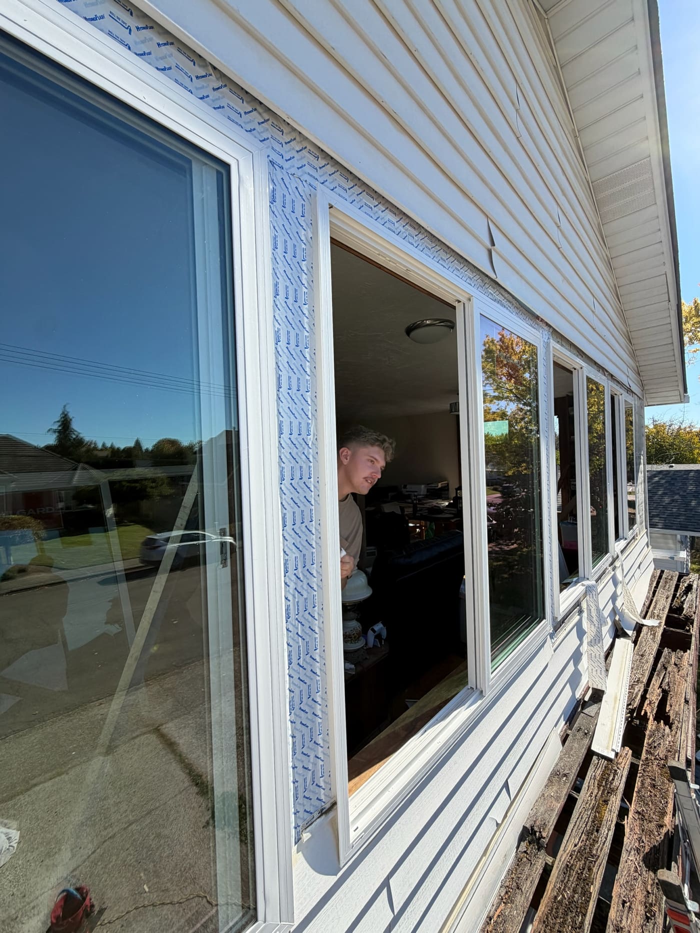 A row of new white windows going into the side of a house, with the old siding pulled off below