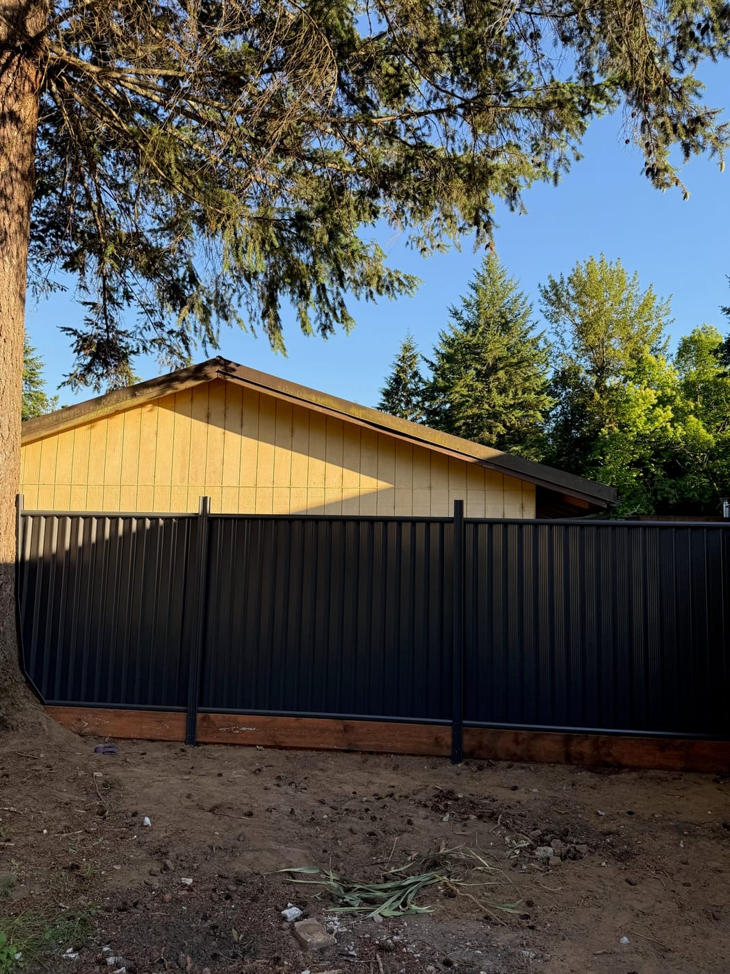 Charcoal metal privacy fence in evening light beside a Portland, OR home, built by Gorilla Works