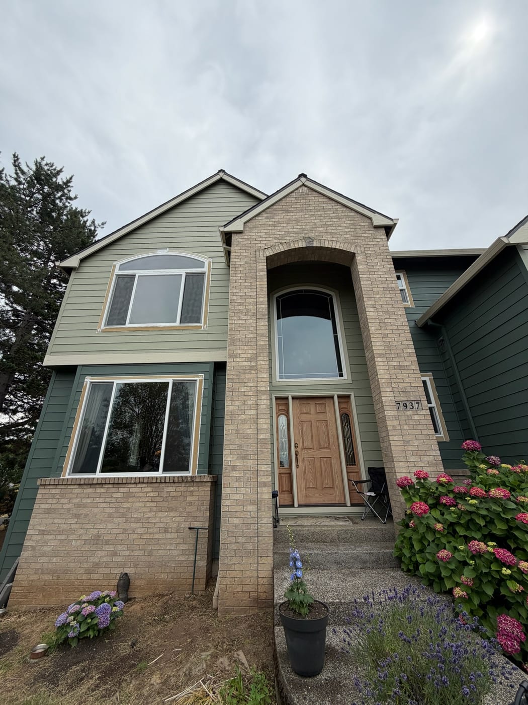Front elevation of a Portland OR home after siding replacement by Gorilla Works, showing the brick entry column and new window trim